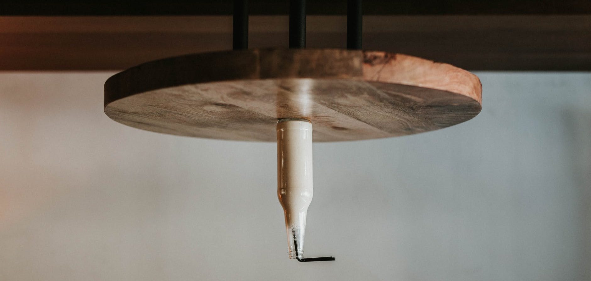 glass bottle filled with black straw on brown wooden table
