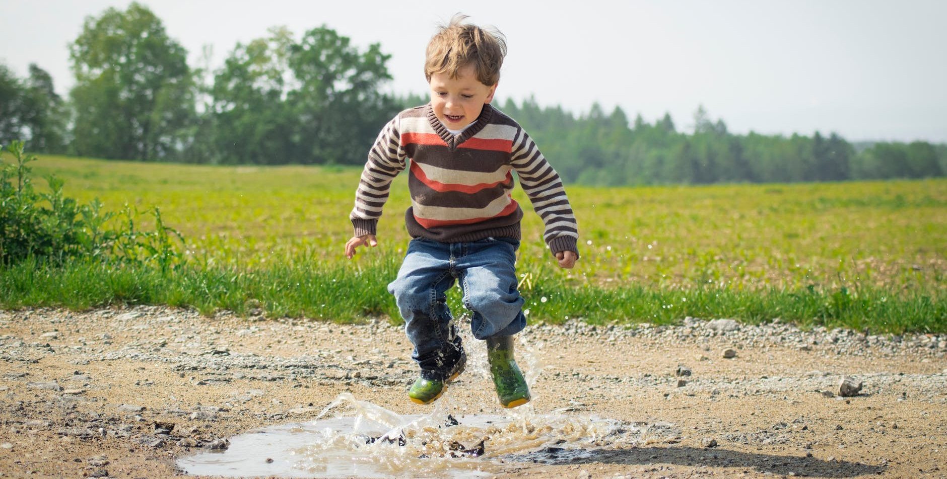 boy jumping near grass at daytime