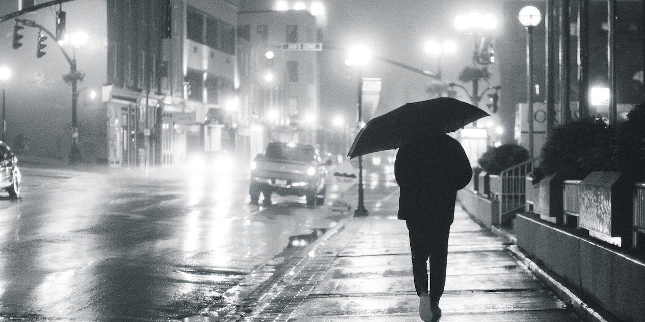 man with umbrella on glowing night street