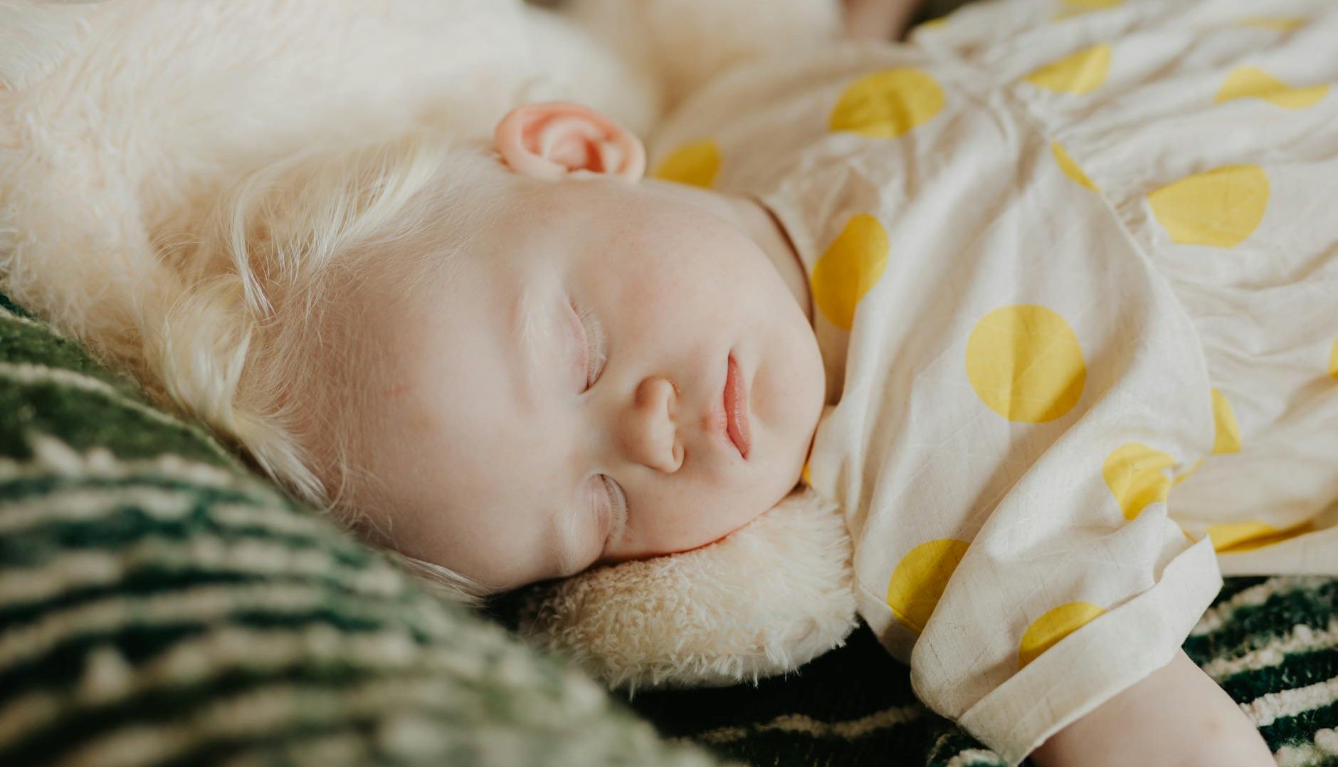baby in white and yellow polka dot dress sleeping