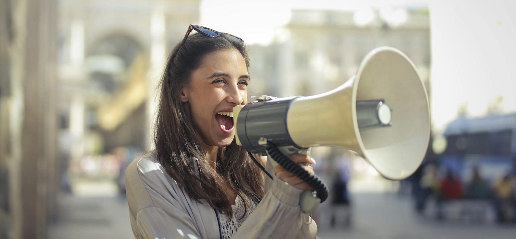 cheerful young woman screaming into megaphone