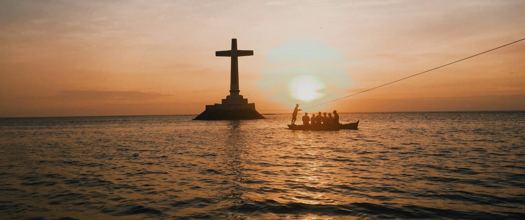 photo of cross in an ocean during dawn